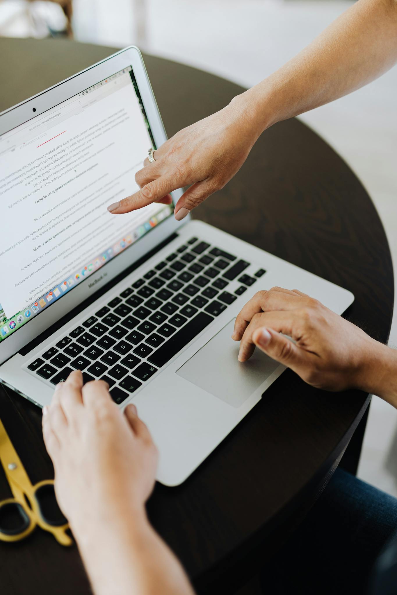 Two individuals collaborate on a laptop project indoors, highlighting teamwork and technology.
